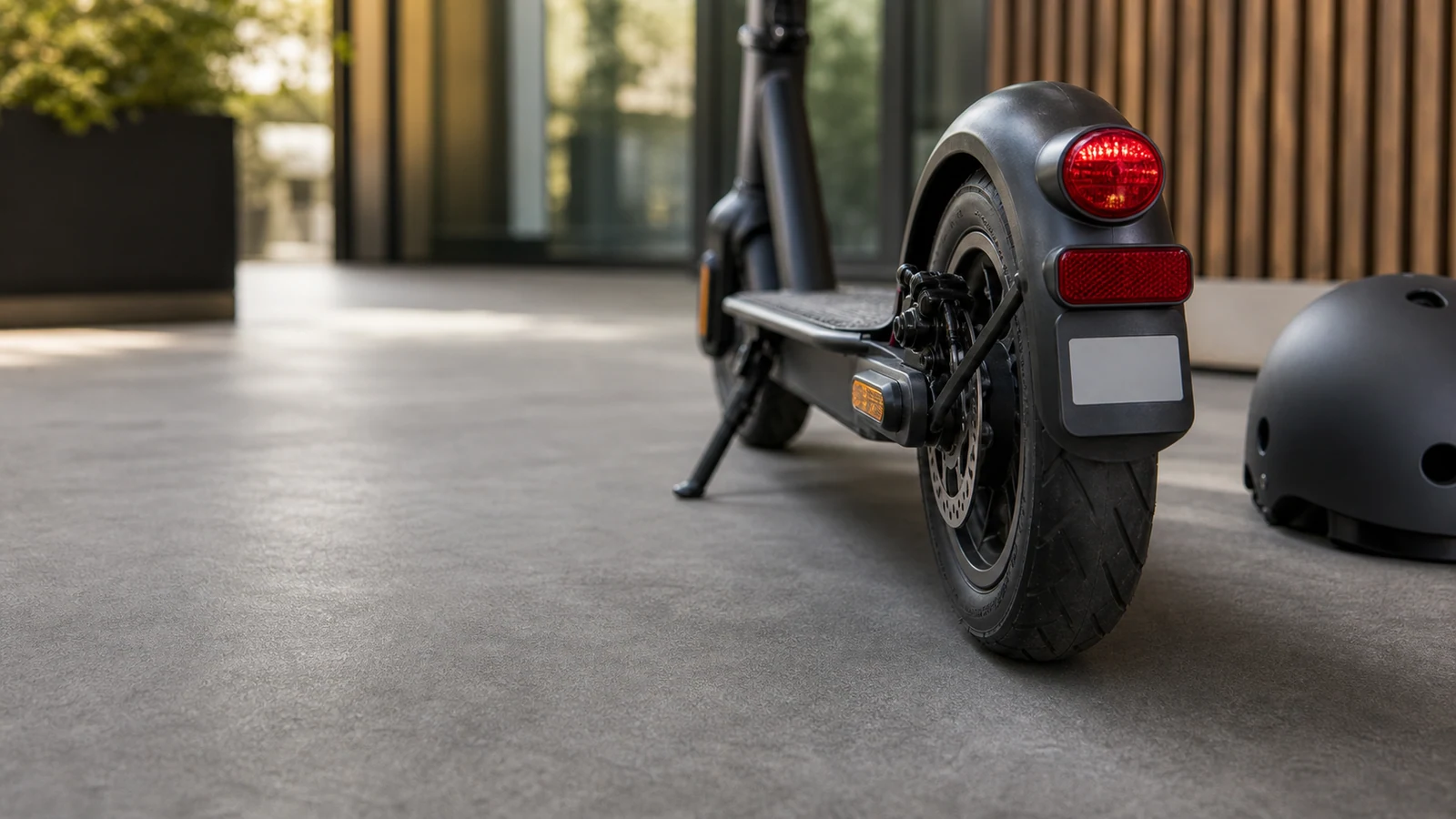 E-Scooter-Heck mit Rücklicht, Versicherungsplakette und Helm in ruhiger Umgebung